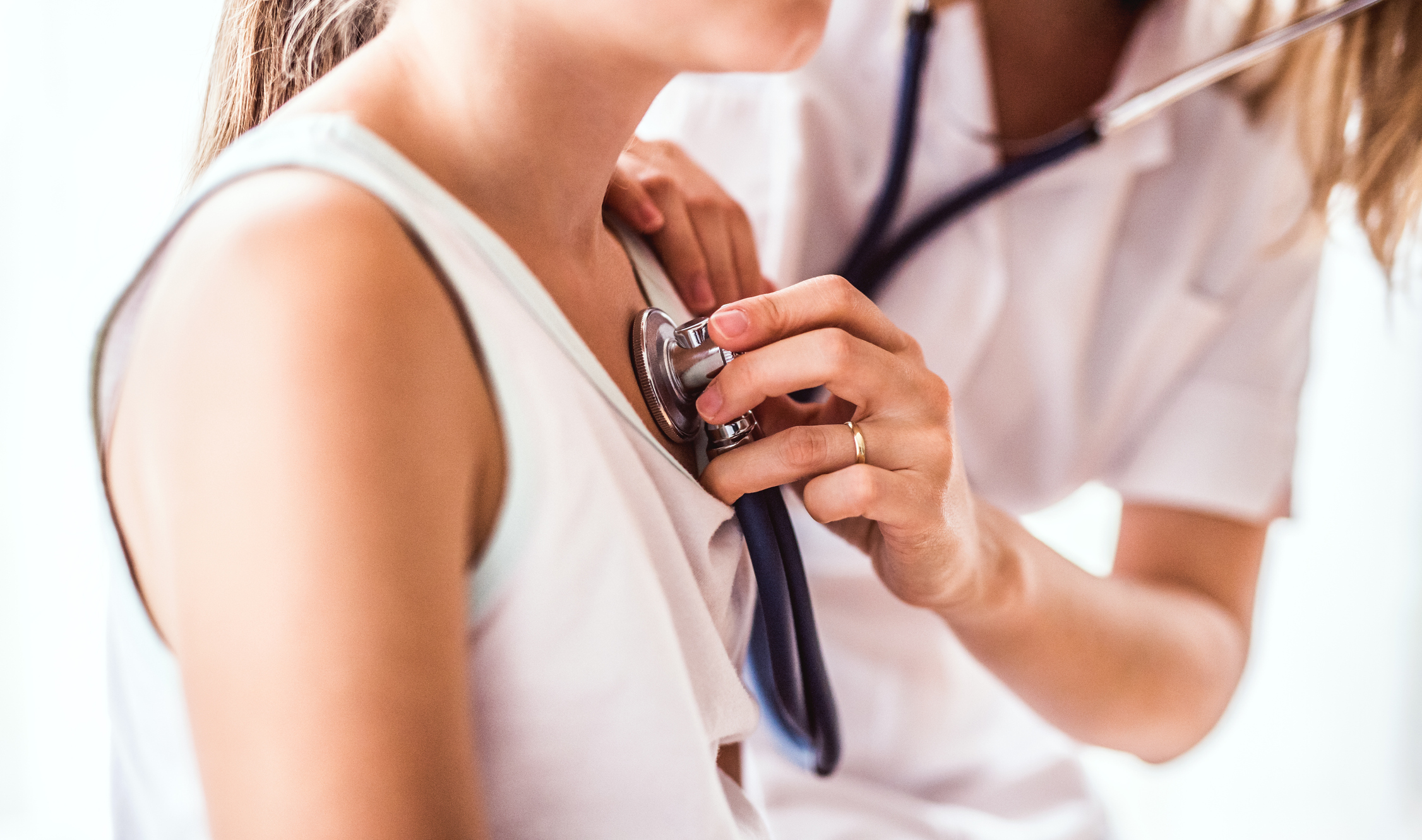 926078462 Unrecognizable young female doctor examining a small girl with stethoscope in her office. Close up.